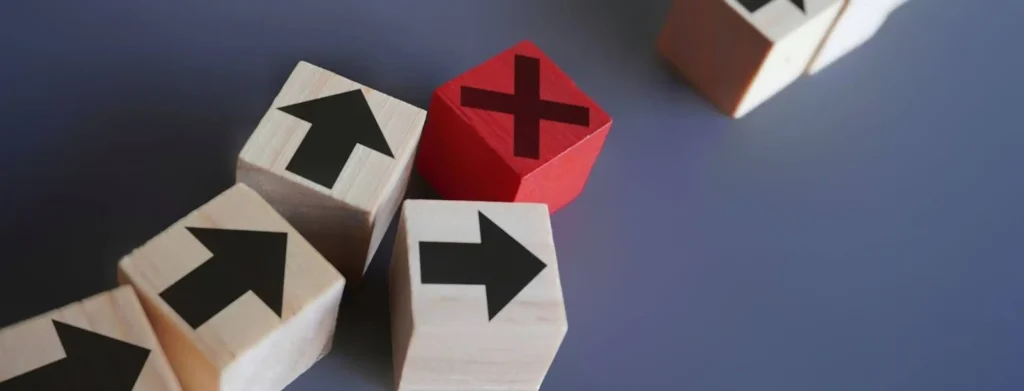 An X-shaped cube disrupting a formation of other cubes marked with directional arrows, symbolising the impact of injunctions and injunction orders in halting or redirecting actions.